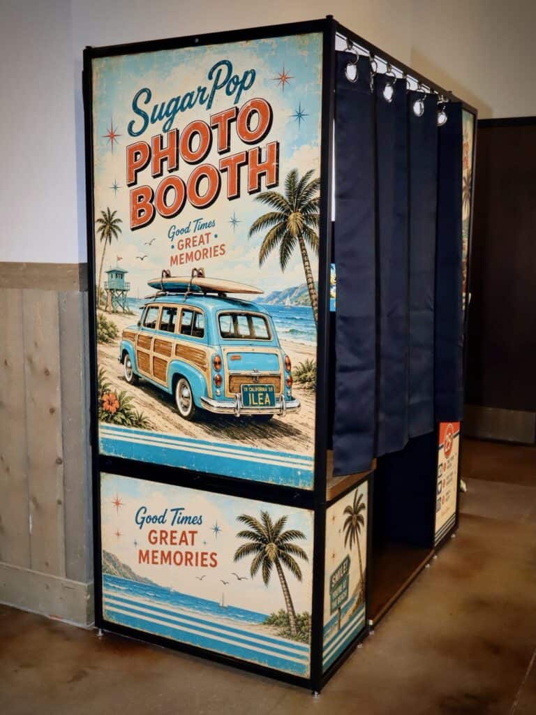 Vintage beach-style enclosed photo booth wrapped with a woody wagon and palm trees at Dick’s Last Resort