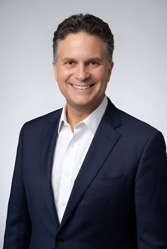 Classic AI headshot of a man in a navy suit on a neutral grey background