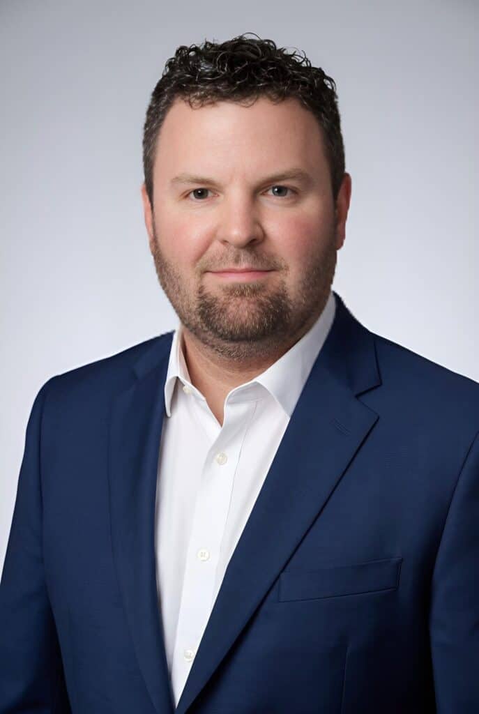 Classic AI headshot of a man in a navy blazer and white shirt on a grey background