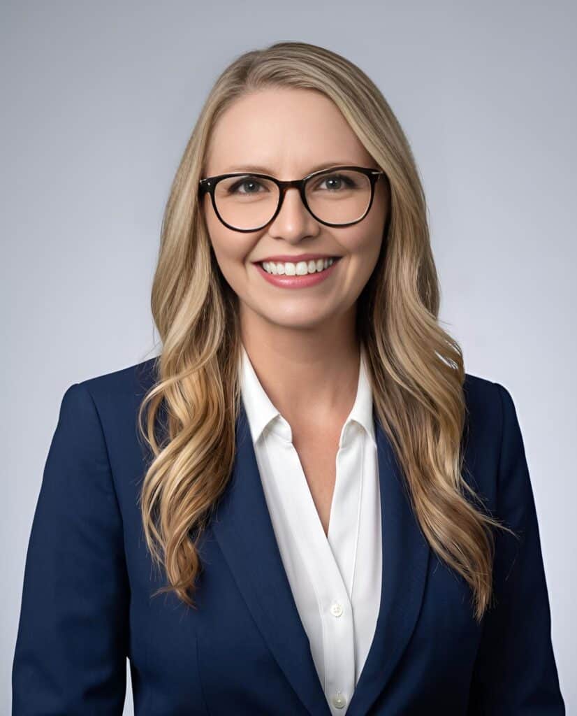 Classic AI headshot of a woman with glasses in a navy blazer on a grey background
